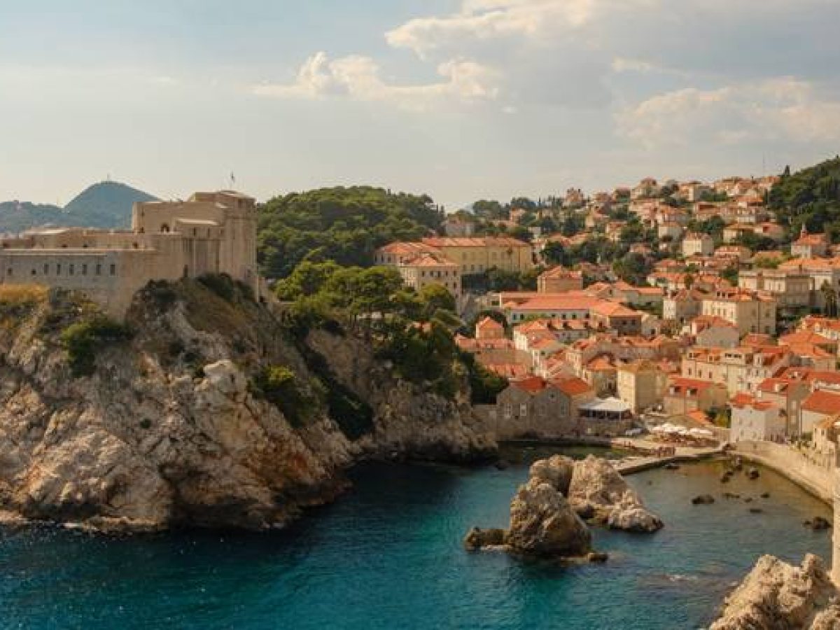 Dubrovnik old town view with historic fortress, terracotta rooftops, medieval city walls, and the sparkling Adriatic coastline in Croatia.